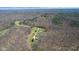 Aerial shot showcasing the home's location amidst a lush, wooded landscape with a pond and winding drive at 6351 Dixon Rd, Columbus, IN 47201