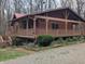 Charming cabin with a metal roof and a spacious, covered wraparound porch nestled in a wooded setting at 6351 Dixon Rd, Columbus, IN 47201