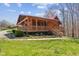 Log cabin with a covered porch and metal roof, showcasing the home's exterior and yard at 6351 Dixon Rd, Columbus, IN 47201