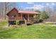 Charming log cabin featuring a red metal roof and covered porch, set on a grassy lawn at 6351 Dixon Rd, Columbus, IN 47201