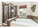 Bathroom featuring a glass shower, soaking tub with window, and neutral earth-tone tile at 6379 Fairfield St, Whitestown, IN 46075