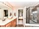 Bathroom featuring double sinks, a mirror with vanity lighting, and a glass shower visible through the doorway at 6379 Fairfield St, Whitestown, IN 46075