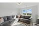 Bright living area with a large gray sectional sofa and a sunny window view at 6476 W Mulberry Way, Greenfield, IN 46140