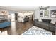 Open-concept living room featuring hardwood floors, a gray sectional sofa, and a view into the kitchen at 694 N Sobota Way, Trafalgar, IN 46181