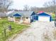 Ranch style home featuring blue trim, a detached two car garage, and a gravel driveway at 7212 E Rocklane Rd, Needham, IN 46162