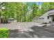 Long paved driveway leads to a three-car garage with an additional garage with lush, green trees at 8990 Pickwick Dr, Indianapolis, IN 46260