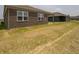A view of the backyard featuring a newly constructed brown brick home with a spacious lawn at 915 Saddlebrook Farms Blvd, Whiteland, IN 46184