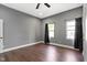 A well-lit bedroom with hardwood floors, gray walls, a ceiling fan, and three windows at 953 Harrison St, Indianapolis, IN 46202