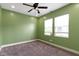 Bedroom with green walls, ceiling fan, neutral carpet, and natural light from a large window at 953 Harrison St, Indianapolis, IN 46202
