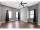 A bright bedroom with hardwood floors, three windows, a ceiling fan, and gray walls at 953 Harrison St, Indianapolis, IN 46202