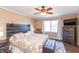A cozy primary bedroom with a wood-accent headboard, ceiling fan, and a large window for natural light at 1002 Corey Ln, Plainfield, IN 46168