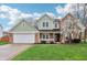 Charming two-story home with a well-manicured lawn, attached garage, and blossoming tree in the front yard at 11117 Harriston Dr, Fishers, IN 46037