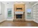 Inviting living room featuring a brick fireplace, built-in shelving, large windows, and hardwood flooring at 11117 Harriston Dr, Fishers, IN 46037