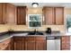 Kitchen featuring wood cabinets, stainless steel dishwasher, double sink and view out the window at 11124 Deer Valley Dr, Indianapolis, IN 46229
