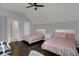 Bedroom with hardwood floors, two beds, and a ceiling fan with door to bathroom at 12535 Glendurgan Dr, Carmel, IN 46032