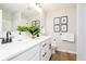 Bathroom with double sink, white cabinets, quartz countertop, black hardware, and decorative plants at 14477 Stairbridge Pl, Carmel, IN 46032