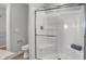 Bright bathroom featuring a glass enclosed shower, seated bench, and grey tiled floor at 15214 Swallow Falls Way, Fishers, IN 46037
