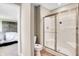 A well-lit bathroom offering a clear glass shower door, a standard toilet, and access to the primary bedroom at 15294 Swallow Falls Way, Fishers, IN 46037