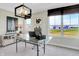 A functional home office features a glass desk, neutral paint, and bright windows offering beautiful views at 15294 Swallow Falls Way, Fishers, IN 46037