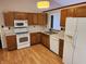 Functional kitchen with wooden cabinets, white appliances, and a window over the sink, ready for Gathering meals at 1657 Park Terrace Ct, Indianapolis, IN 46229