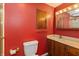 Cozy bathroom with red walls, vanity with storage, and a toilet, offering a functional space at 1665 South Dr, Columbus, IN 47203