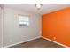 Cozy bedroom with orange accent wall, window, and wood-look floors at 1665 South Dr, Columbus, IN 47203