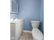 This bathroom features a gray vanity, toilet, blue walls, and tile flooring at 2501 Reformers Ave, Indianapolis, IN 46203