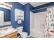 Compact bathroom with a vanity, toilet, and shower/tub combination featuring bright blue walls and colorful shower curtain at 329 Dogwood Dr, Pendleton, IN 46064
