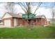 Backyard view of a brick house featuring a 2-car garage and a green tree fort at 4411 W Friar Dr, Muncie, IN 47304