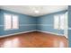 Spacious bedroom with hardwood floors, two windows, blue walls, and a ceiling fan at 4411 W Friar Dr, Muncie, IN 47304