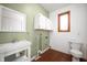 Laundry room featuring a sink, toilet, cabinets, window, and wood flooring at 4411 W Friar Dr, Muncie, IN 47304