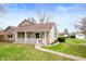 Charming stone home with a covered front porch and manicured lawn at 453 S High School Rd, Indianapolis, IN 46241