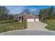 Aerial view of a well-manicured brick home with a large driveway, three-car garage, basketball hoop and mature trees at 4644 S Grassy Ct, New Palestine, IN 46163