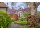 View of backyard with wood deck, colorful landscaping, trees, and manicured bushes at 6141 Madison Ave, Indianapolis, IN 46227