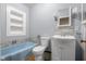 Bathroom with a blue bathtub, tiled niche, toilet, and vanity with a sink at 6141 Madison Ave, Indianapolis, IN 46227