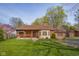 Charming brick home featuring a covered porch, bay window, and mature trees at 6141 Madison Ave, Indianapolis, IN 46227