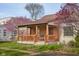 Charming brick home with a covered front porch and blooming redbud trees at 6141 Madison Ave, Indianapolis, IN 46227