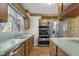 Bright kitchen with stainless steel appliances, wood cabinets, light green countertops, and floral wallpaper border at 6141 Madison Ave, Indianapolis, IN 46227