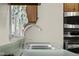 Kitchen sink with chrome fixtures and a green countertop, beneath a window with patterned curtains at 6141 Madison Ave, Indianapolis, IN 46227