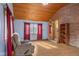 Bright living room featuring a brick accent wall, wood-paneled ceiling, and large windows at 6141 Madison Ave, Indianapolis, IN 46227
