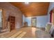 Bright living room featuring a brick accent wall, wood-paneled ceiling, and hardwood flooring at 6141 Madison Ave, Indianapolis, IN 46227