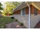 View of the side of the home featuring a red and white shed, brick details, and greenery around the house at 6144 S Irwin St, Indianapolis, IN 46237