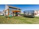 Wide shot of a backyard, displaying trampoline, patio seating under a wooden pergola, and swing set at 6767 Sonora Blvd, Brownsburg, IN 46112