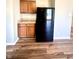 Kitchenette area featuring wood cabinets, countertops, a black refrigerator, and new wood flooring at 8051 Retreat Ln, Indianapolis, IN 46259