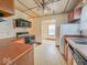 A compact kitchen featuring wood cabinets, a white refrigerator, laminate countertops, and vinyl flooring at 831 Wallace Ave, Indianapolis, IN 46201