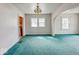 A living room with green carpet, white walls, multiple windows, and an archway with an open doorway to the kitchen at 831 Wallace Ave, Indianapolis, IN 46201