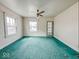 A living room with green carpet, white walls, multiple windows, and a ceiling fan with light at 831 Wallace Ave, Indianapolis, IN 46201