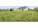 A spacious backyard features a lush lawn and houses in the background, creating an inviting outdoor space at 8660 Benjamin Ln, Avon, IN 46123
