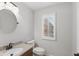 Bright powder room with a round mirror, granite countertop, and a white toilet next to the window at 8939 Spider Bay Ct, Indianapolis, IN 46236