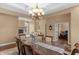 Dining room with glass top dining table and decorative chandelier with a view to the living room at 9877 Wading Crane Ave, Fishers, IN 46055